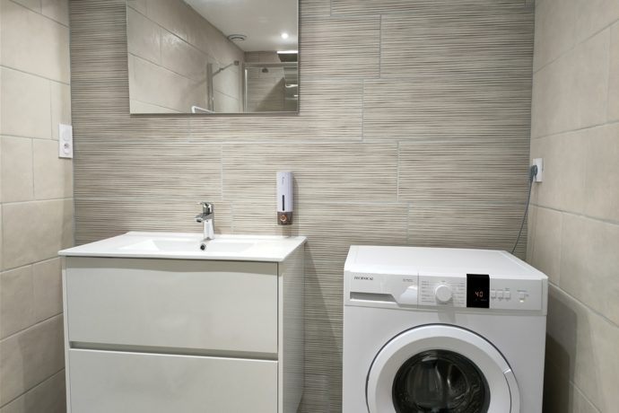 Salle de bains : miroir, lavabo, lave-linge.